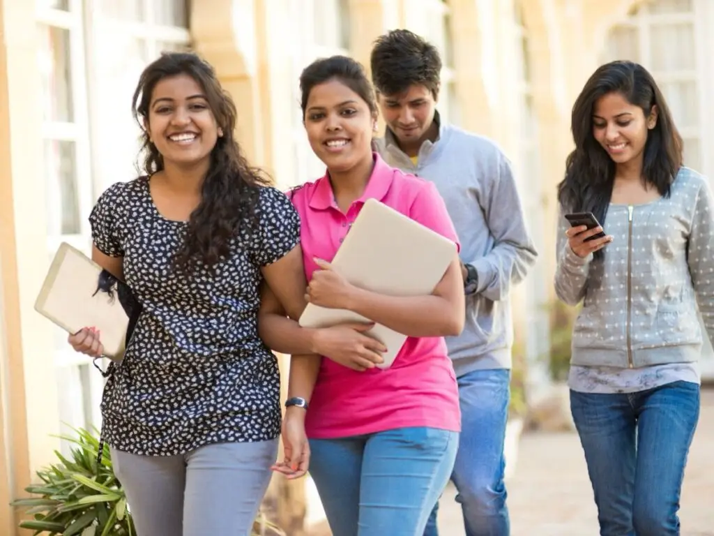 College students walking together on campus with books and laptops.